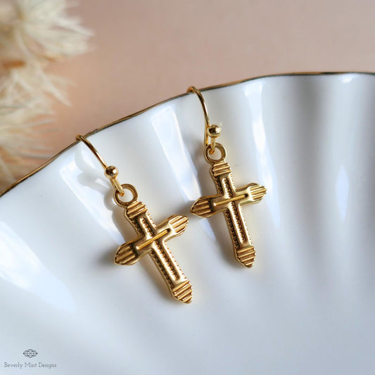 A pair of gold cross-shaped earrings with a scalloped design, displayed on a white surface.