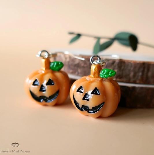 a pair of pumpkin earrings sitting on top of a table