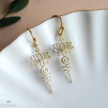 A pair of gold earrings with intricate floral designs, resting on a white plate.