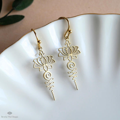 A pair of gold earrings with intricate floral designs, displayed on a white plate.