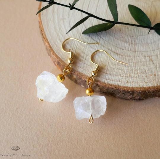 a pair of earrings with a white rock hanging from it