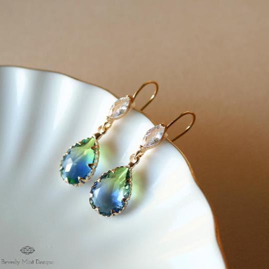 a pair of earrings sitting on top of a white plate